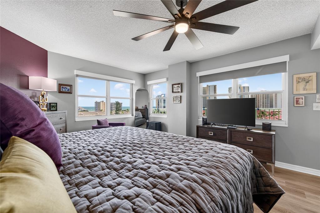 A bedroom features a bed, a television on a dresser, and windows overlooking the ocean — 4 OCEANS WEST BOULEVARD UNIT 705D, DAYTONA BEACH, FL