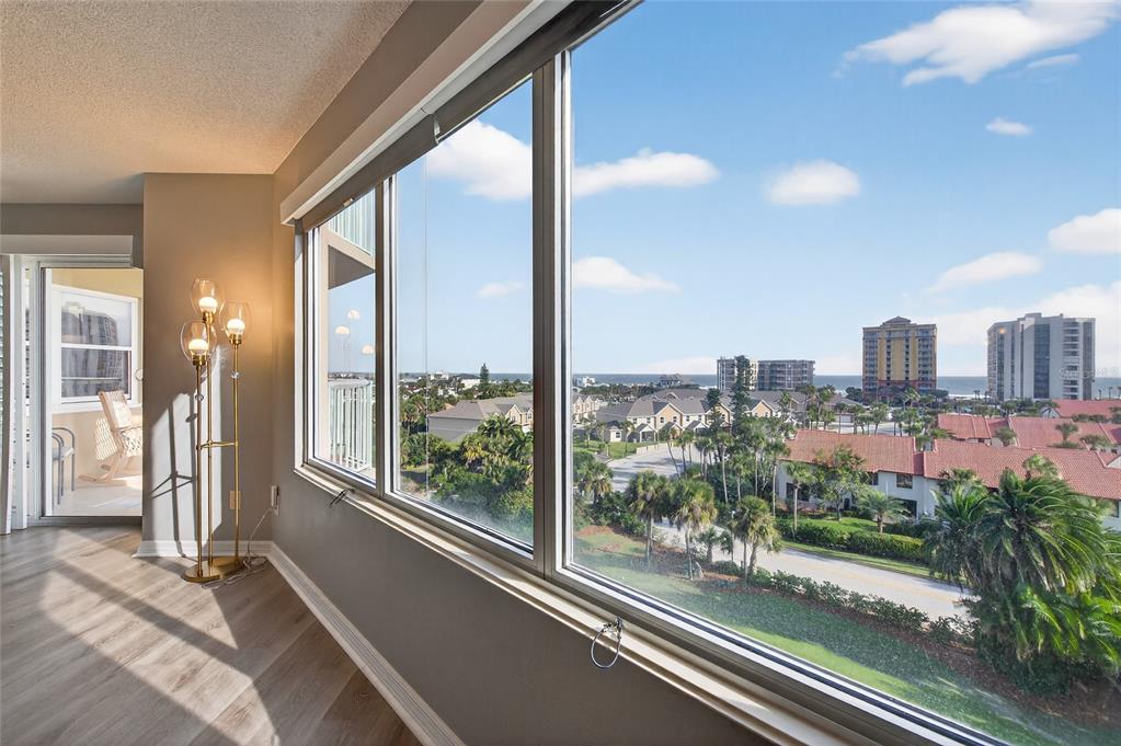A room with light wood flooring and a floor lamp overlooks a coastal residential area — 4 OCEANS WEST BOULEVARD UNIT 705D, DAYTONA BEACH, FL