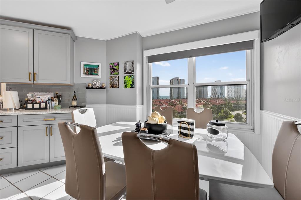 A dining area features a white table, tan chairs, gray cabinets, and a window view — 4 OCEANS WEST BOULEVARD UNIT 705D, DAYTONA BEACH, FL