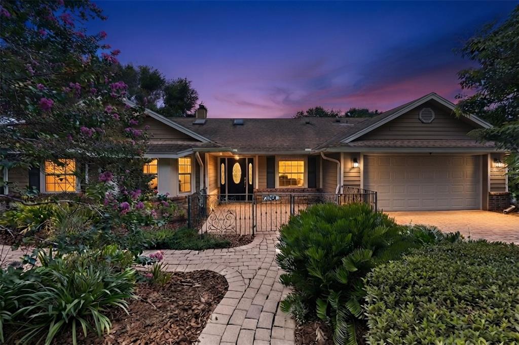 A single-story house with a paved walkway, gated courtyard, and attached garage at dusk — 4507 WINDERWOOD CIRCLE, ORLANDO, FL