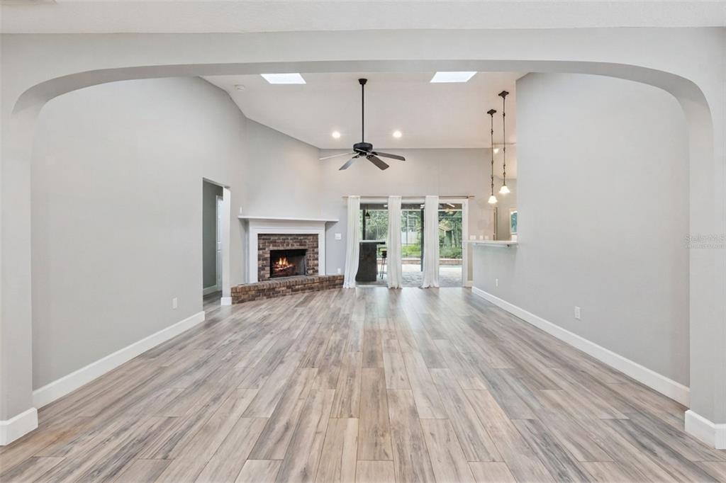 A living room with light wood flooring, a brick fireplace, and a ceiling fan — 4507 WINDERWOOD CIRCLE, ORLANDO, FL