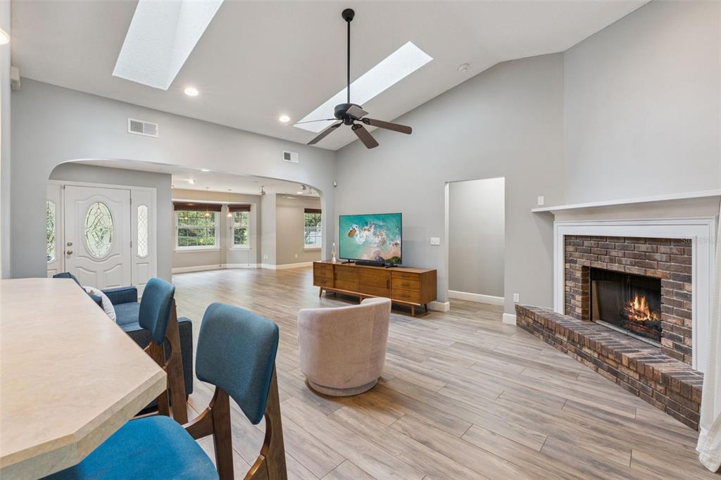 A living room features a brick fireplace, vaulted ceilings with skylights, and wood-look flooring — 4507 WINDERWOOD CIRCLE, ORLANDO, FL