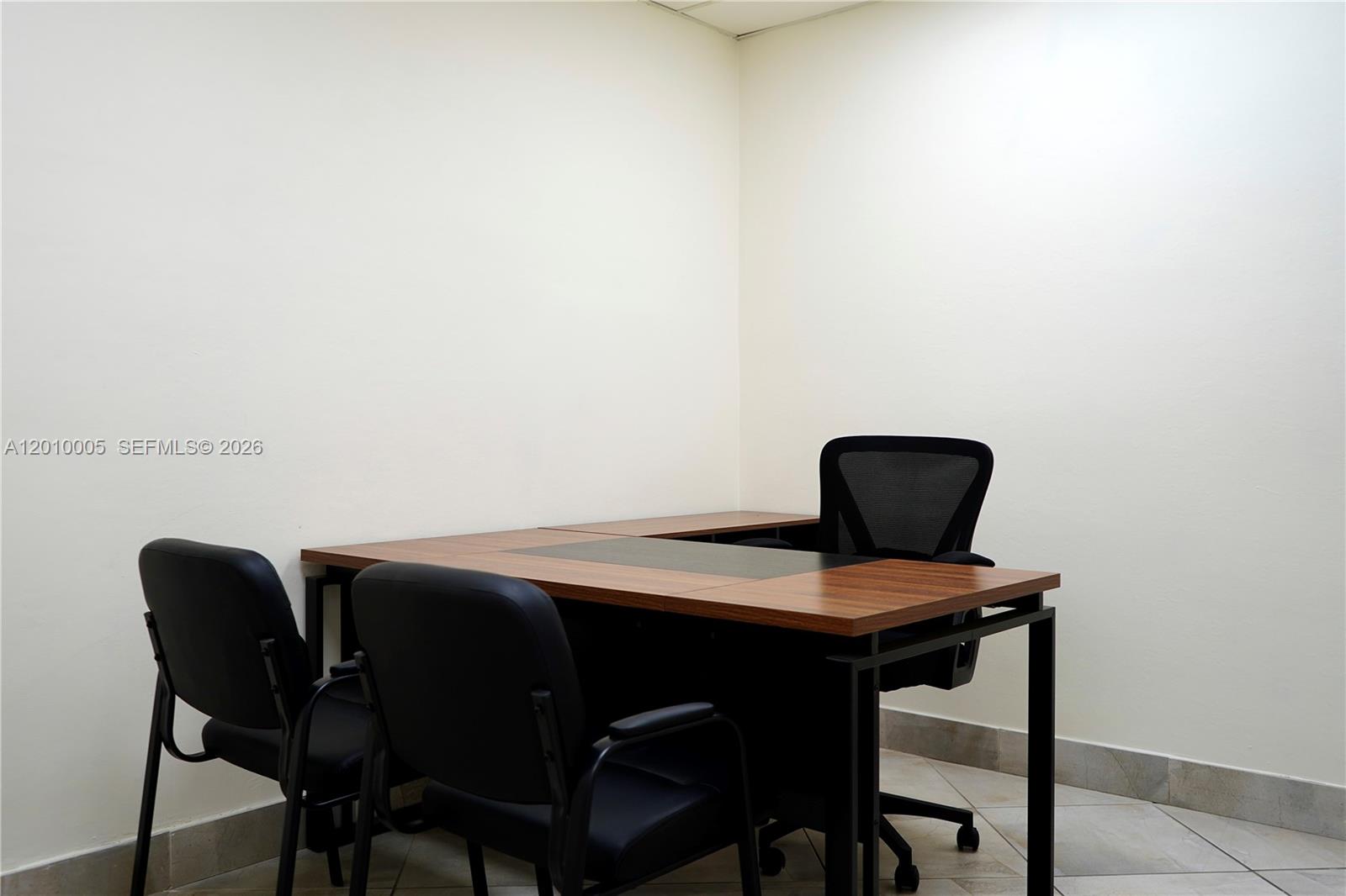 An office room features a wooden desk with a black frame and three black chairs — 150 Westward Dr # 5, Miami Springs FL 33166, MIAMI SPRINGS, FL