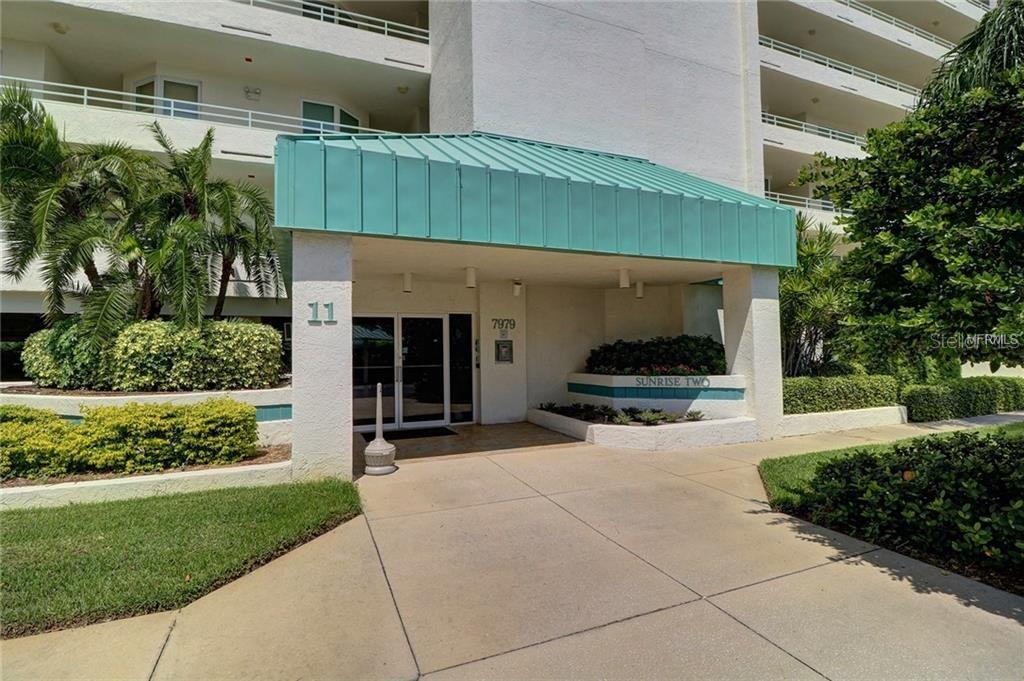 The exterior entrance of a multi-story residential building features a teal metal awning — 7979 SAILBOAT KEY BOULEVARD S UNIT 306, SOUTH PASADENA, FL