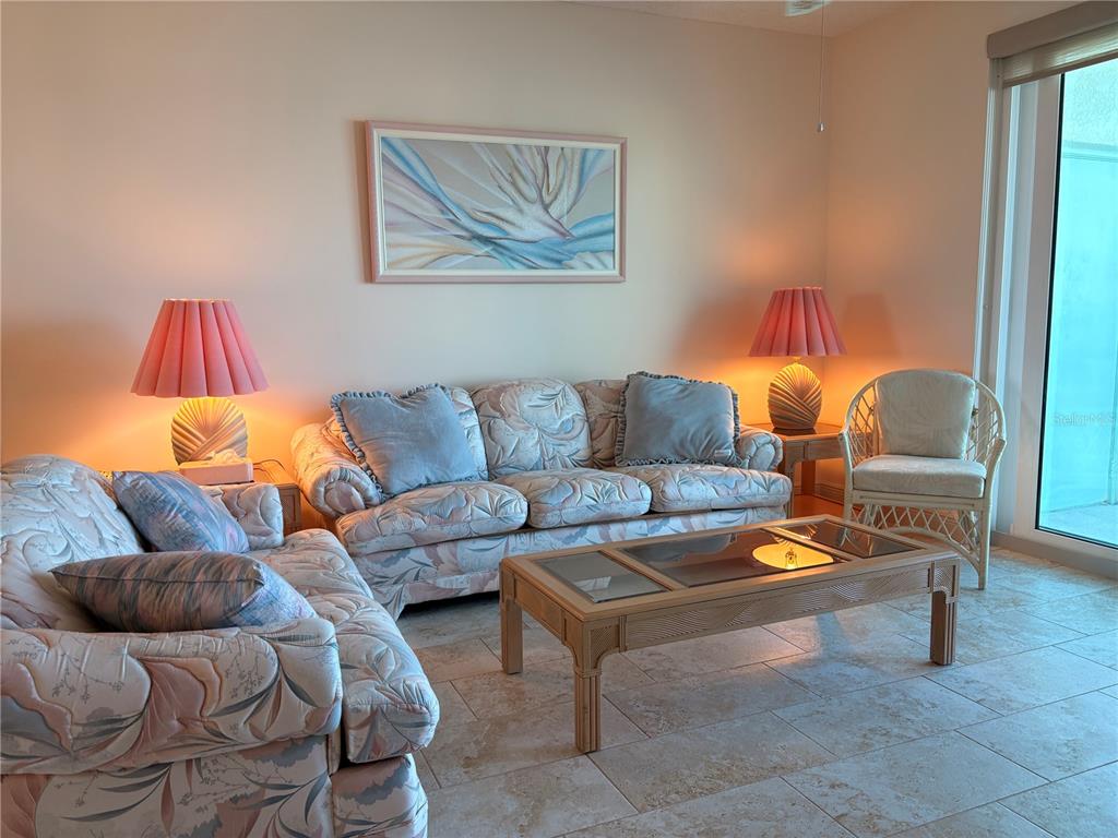 A living room features patterned sofas, a glass-top coffee table, and two pink table lamps — 7979 SAILBOAT KEY BOULEVARD S UNIT 306, SOUTH PASADENA, FL