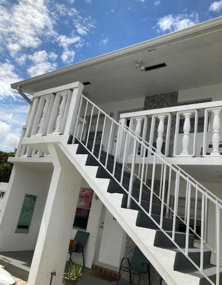 An exterior view of a two-story building featuring a white staircase and balcony railing — 602 N H Street # 1a, FL 33460, FL
