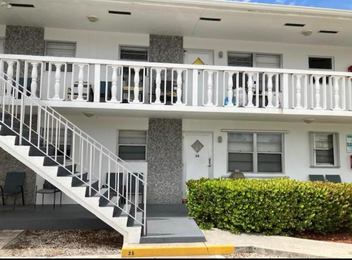 A two-story apartment building exterior features a white staircase, balcony railings, and unit 2A — 602 N H Street # 1a, FL 33460, FL
