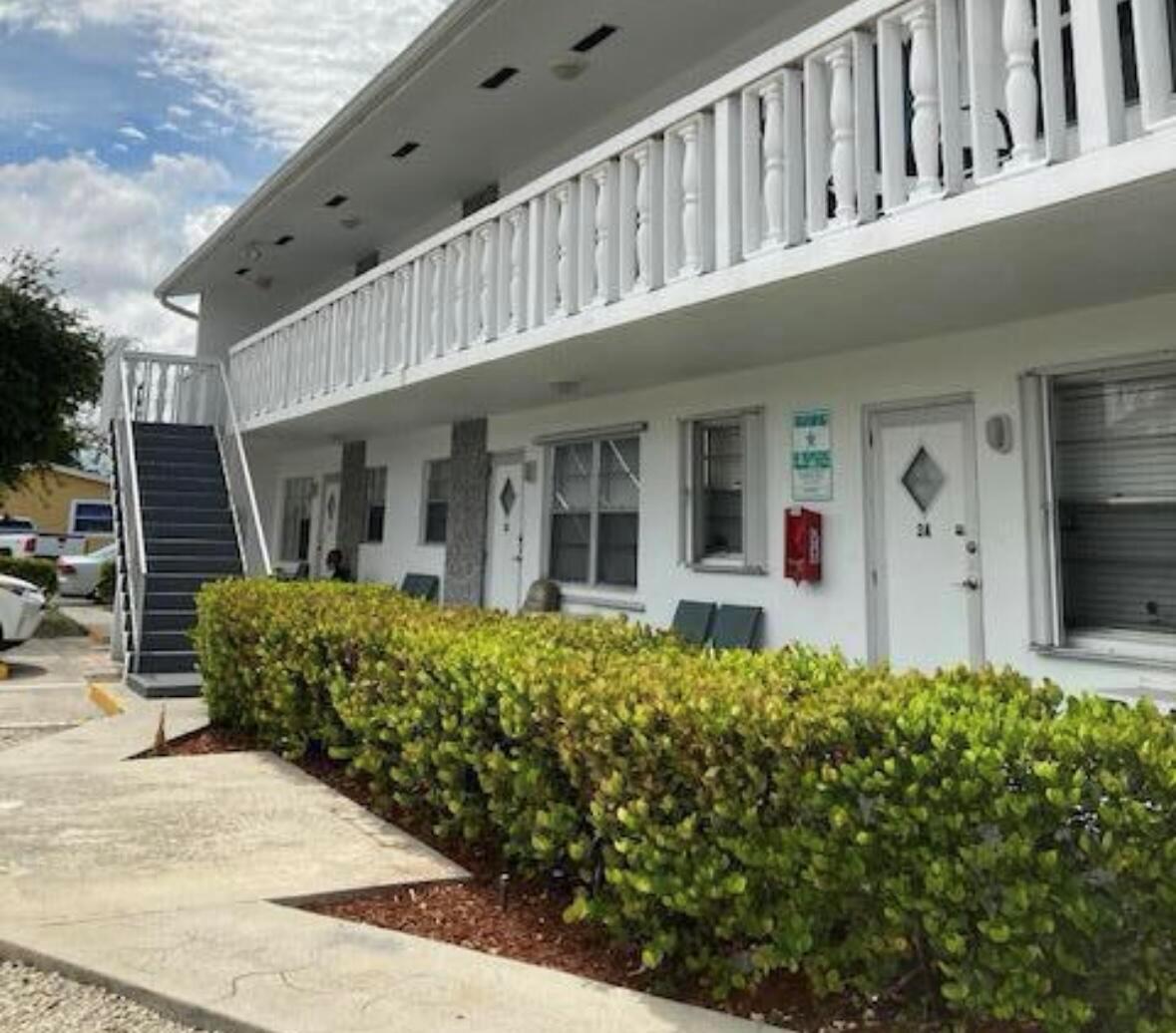 A two-story apartment building with a white exterior, a balcony, and a hedge-lined walkway — 602 N H Street # 1a, FL 33460, FL
