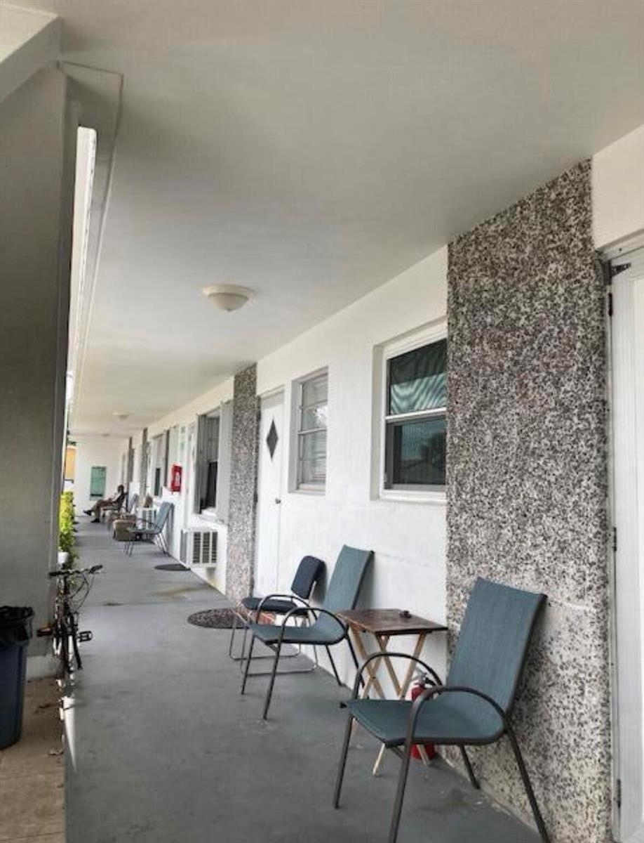 An outdoor covered walkway features a row of chairs, windows, and textured stone wall accents — 602 N H Street # 1a, FL 33460, FL