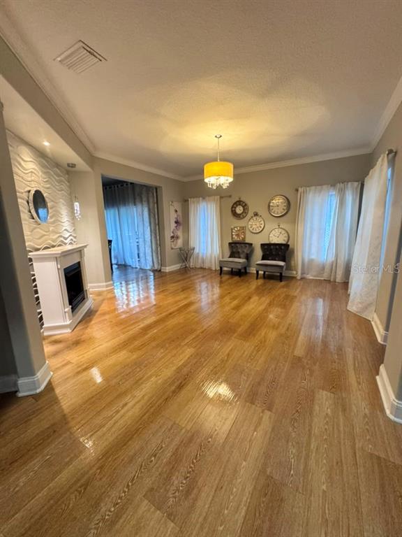 A living room features light hardwood floors, a white fireplace, and a yellow pendant light — 6956 BRESCIA WAY, ORLANDO, FL