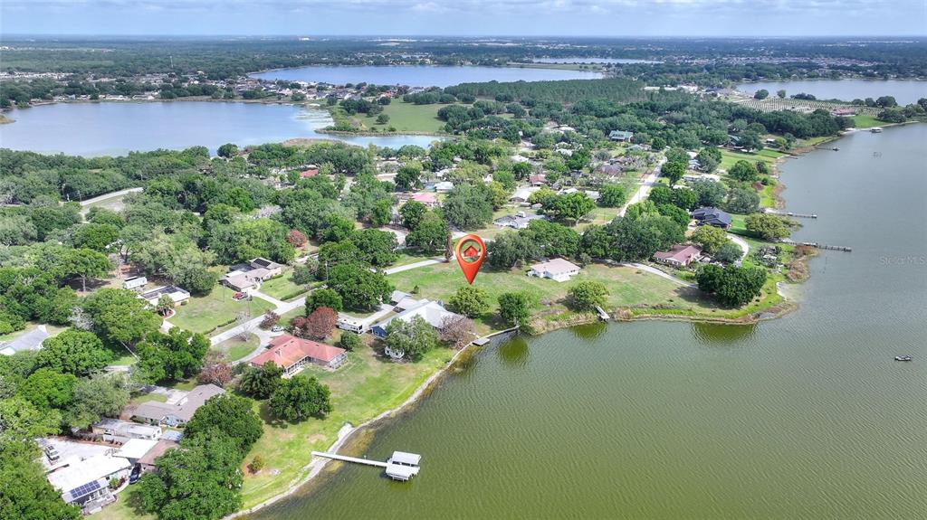 An aerial view shows a waterfront property with a dock and a red location pin — LAKE AVENUE, WINTER HAVEN, FL
