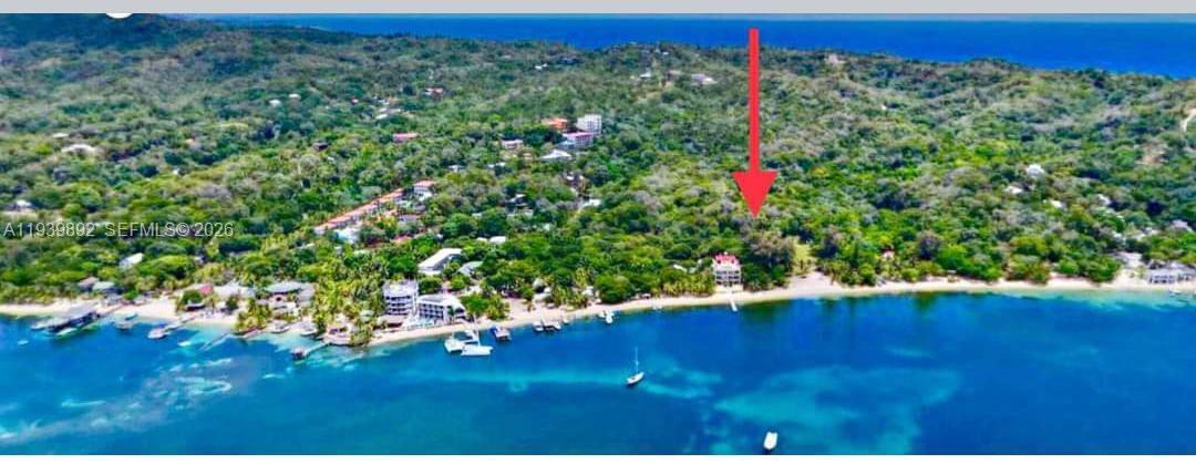 Aerial view of a coastal property with a multi-story building situated on a sandy beach — Roatan Island at Caribbean, Honduras, NA, NA