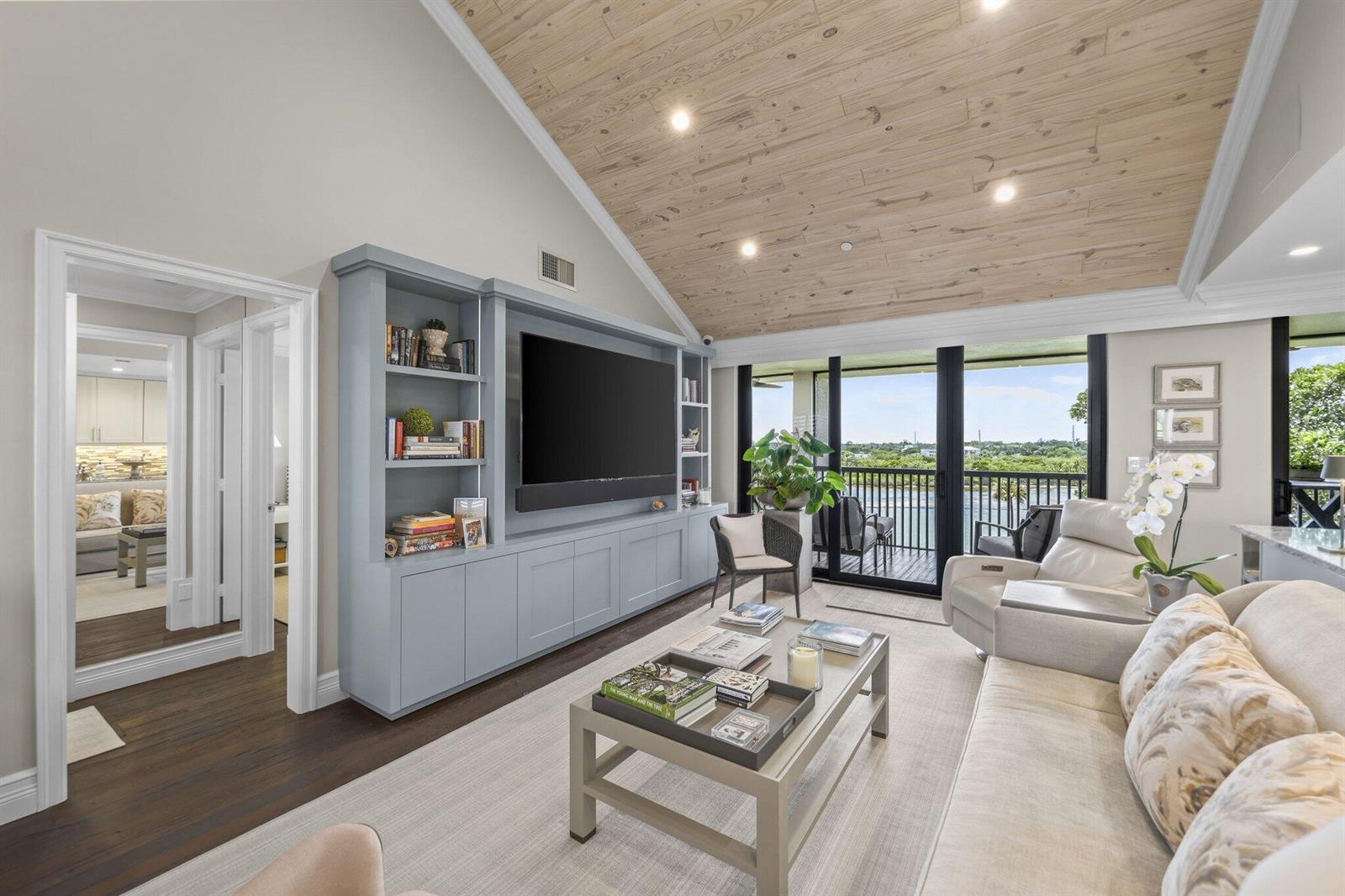 A living room features a blue built-in media center, vaulted wood ceiling, and balcony access — 1000 N Us Highway 1, Jupiter FL 33477, JUPITER, FL