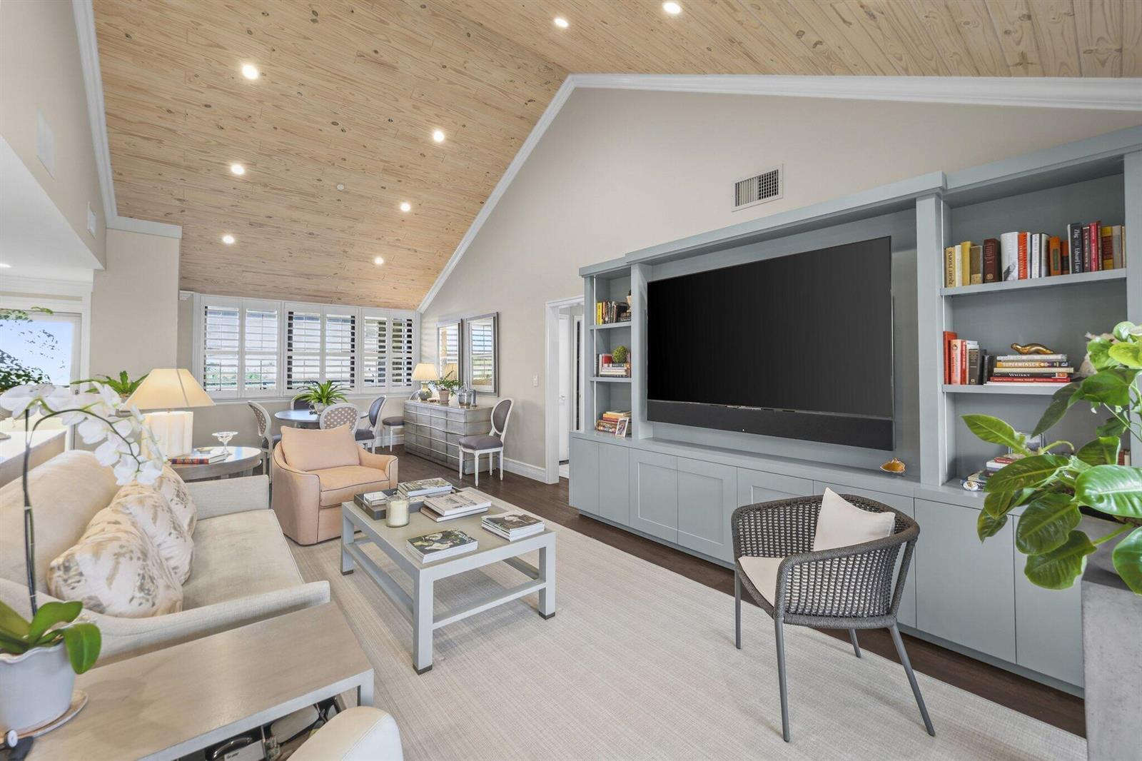 A living room features a vaulted wood-paneled ceiling, built-in cabinetry, and a large television — 1000 N Us Highway 1, Jupiter FL 33477, JUPITER, FL