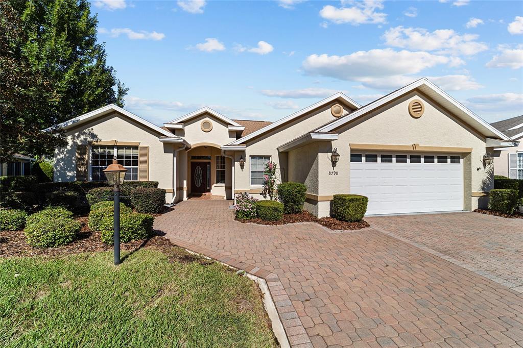 A single-story house with a beige stucco exterior, a brick paver driveway, and a garage — 8798 SW 83RD CIRCLE, OCALA, FL