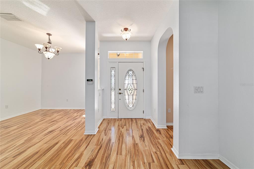 An entryway features a white front door with a decorative oval glass insert and wood flooring — 8798 SW 83RD CIRCLE, OCALA, FL