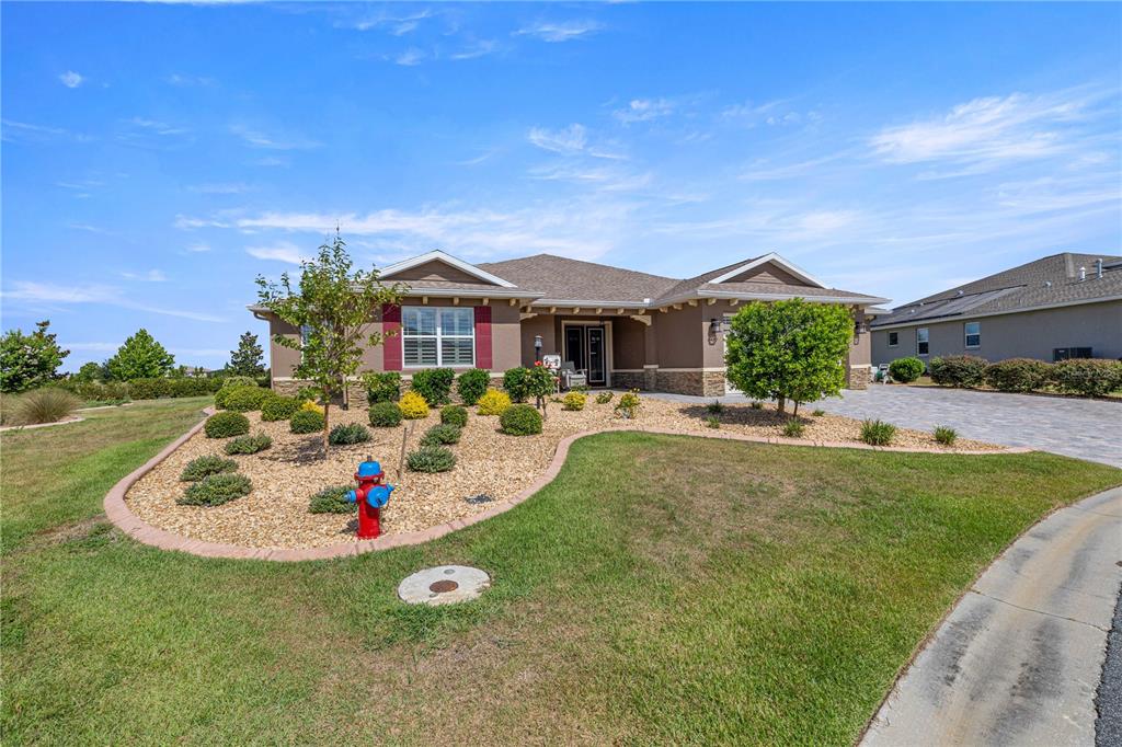 A single-story house with a stone-accented facade, a paved driveway, and a front yard garden — 8477 SW 93RD CIRCLE, OCALA, FL