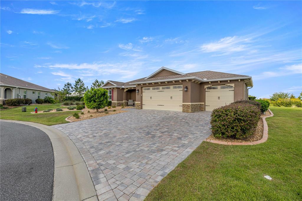 A single-story house with a paved driveway, three-car garage, and landscaped front yard — 8477 SW 93RD CIRCLE, OCALA, FL