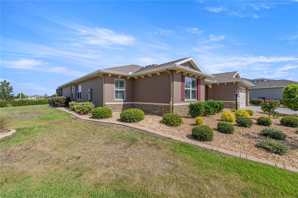 A single-story house with brown stucco walls, stone veneer, and a landscaped rock garden — 8477 SW 93RD CIRCLE, OCALA, FL