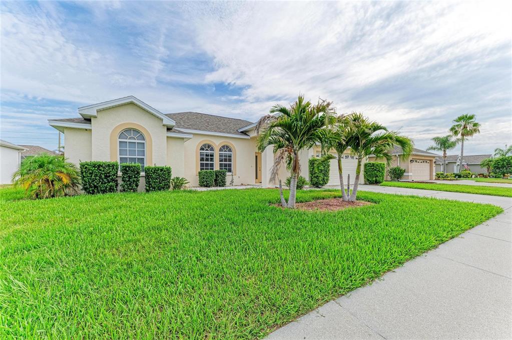 A single-story house with a beige stucco exterior, palm trees, and a green lawn — 3213 45TH AVENUE E, BRADENTON, FL