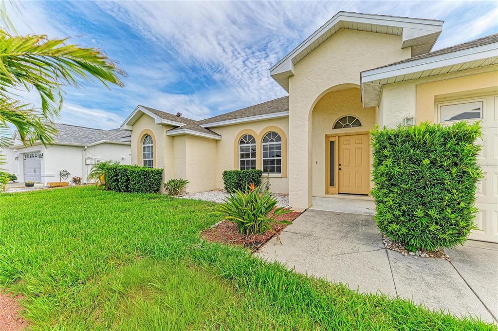 A single-story house with a beige stucco exterior, arched entryway, and a green front lawn — 3213 45TH AVENUE E, BRADENTON, FL