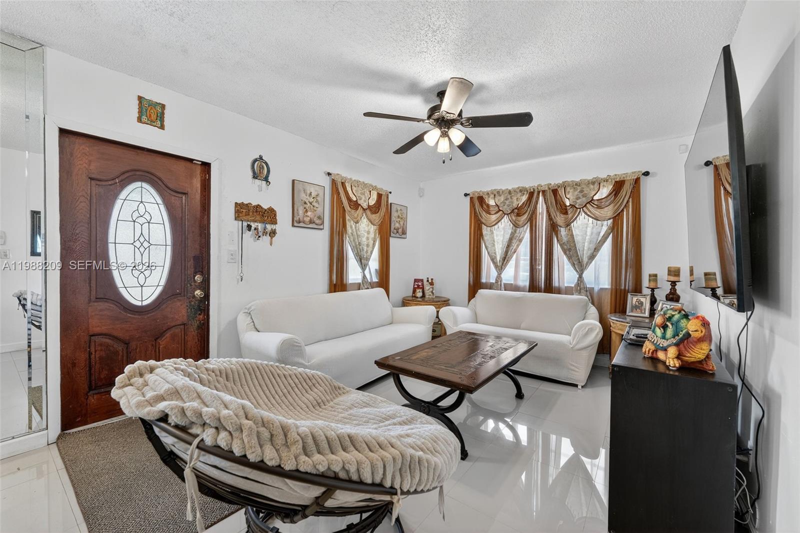 A living room features white sofas, a coffee table, a papasan chair, and a wooden door — 26672 SW 137th Ct, Miami FL 33032, MIAMI, FL