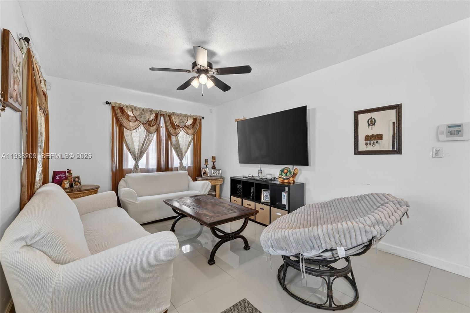 A living room features white sofas, a wooden coffee table, a television, and a chair — 26672 SW 137th Ct, Miami FL 33032, MIAMI, FL