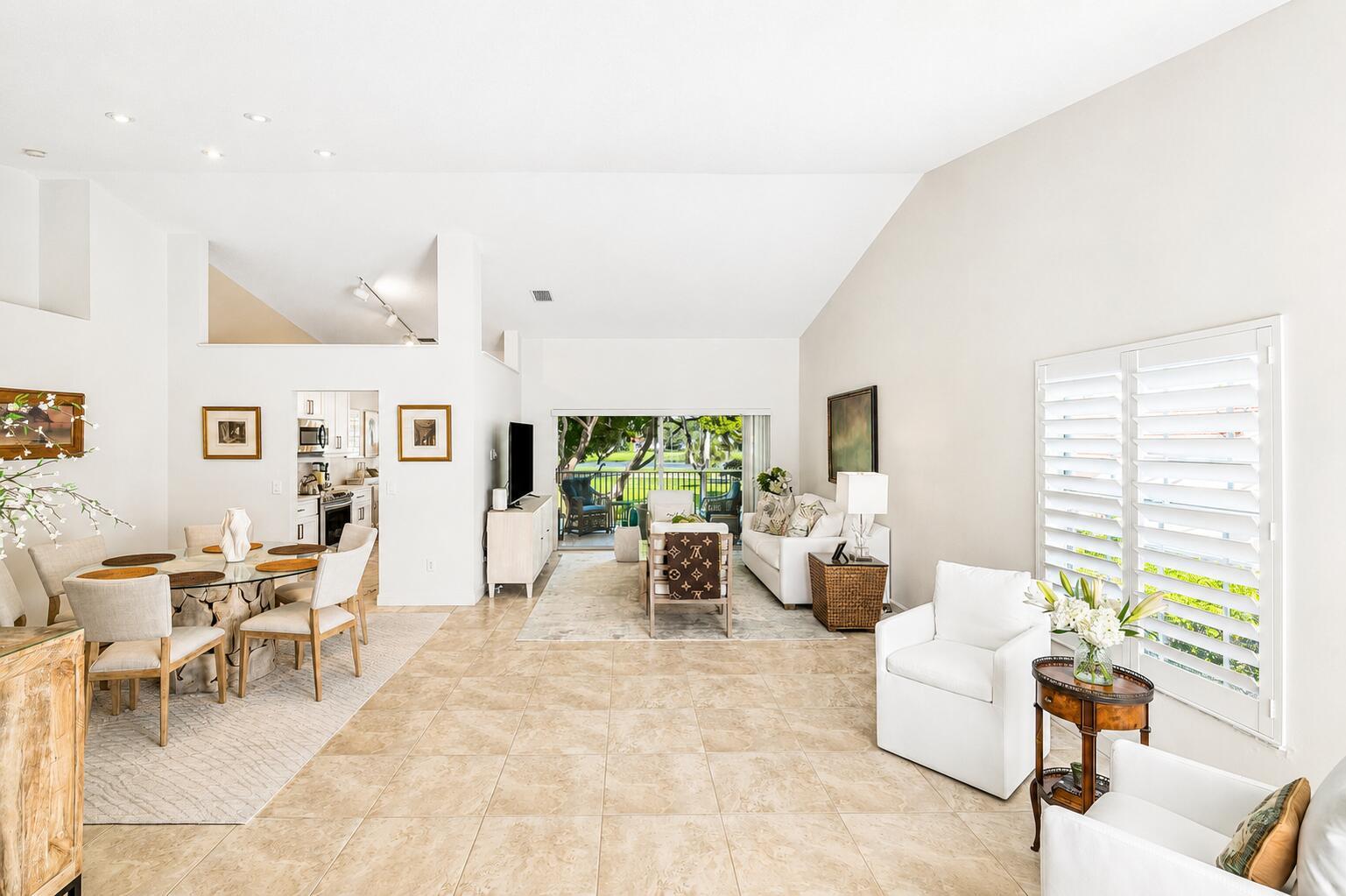 A bright, open-concept living and dining area features tile flooring, vaulted ceilings, and patio access — 17061 Emile Street # 5, Boca Raton FL 33487, BOCA RATON, FL
