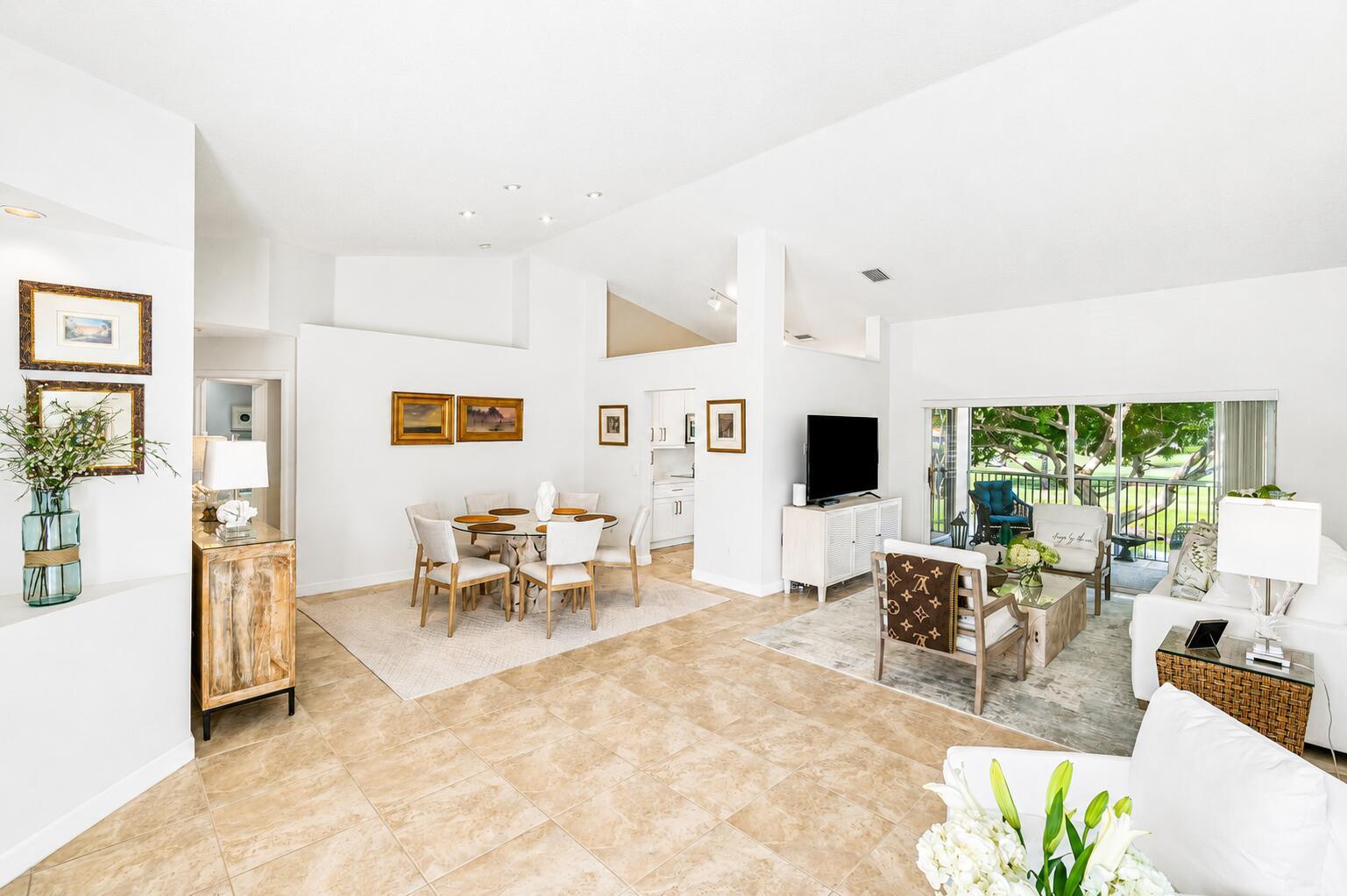A bright, open-concept living and dining area features tile flooring, white walls, and large windows — 17061 Emile Street # 5, Boca Raton FL 33487, BOCA RATON, FL