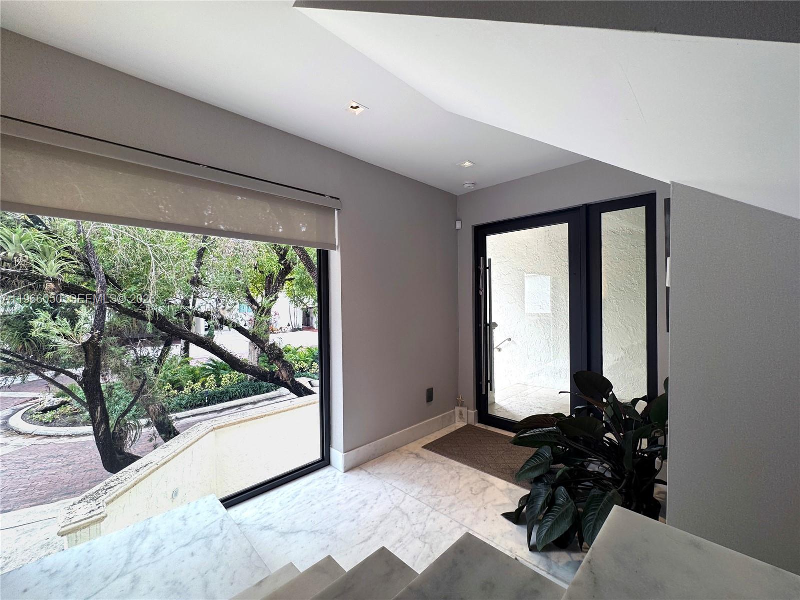 An entryway features marble flooring, a large window overlooking trees, and a glass front door — 2000 S Bayshore Drive # 13, Miami FL 33133, MIAMI, FL