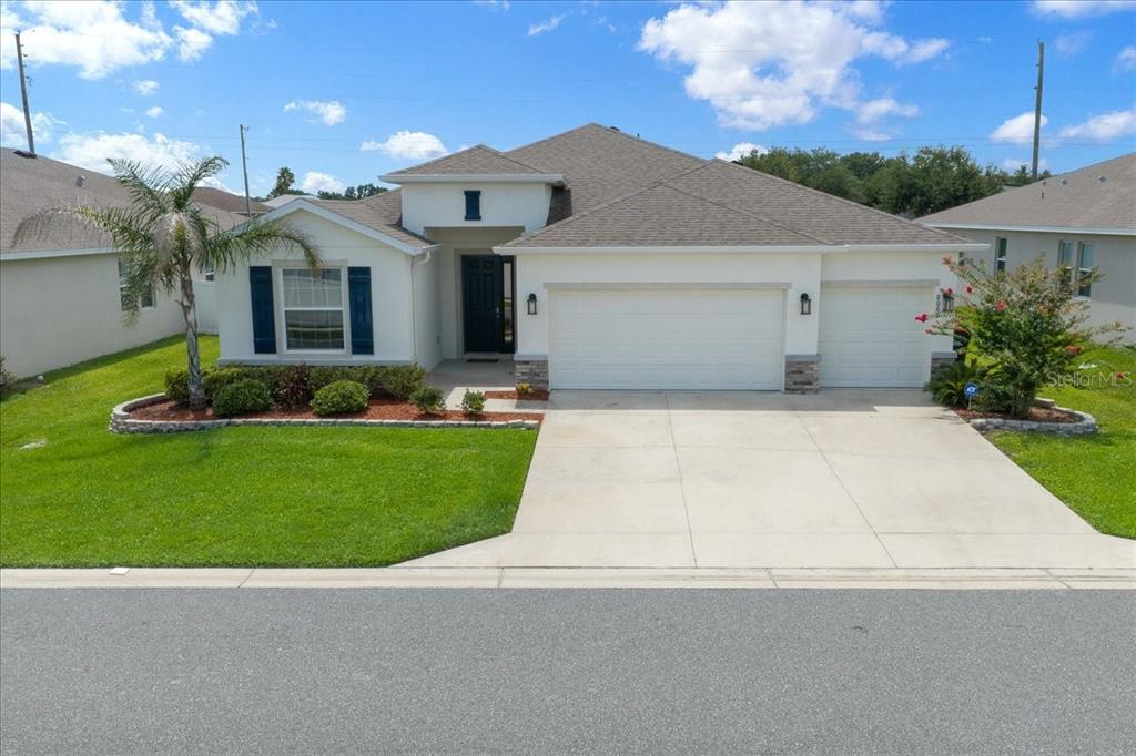 A single-story suburban house with a white stucco exterior, a three-car garage, and a lawn — 8068 SW 59TH TERRACE, OCALA, FL
