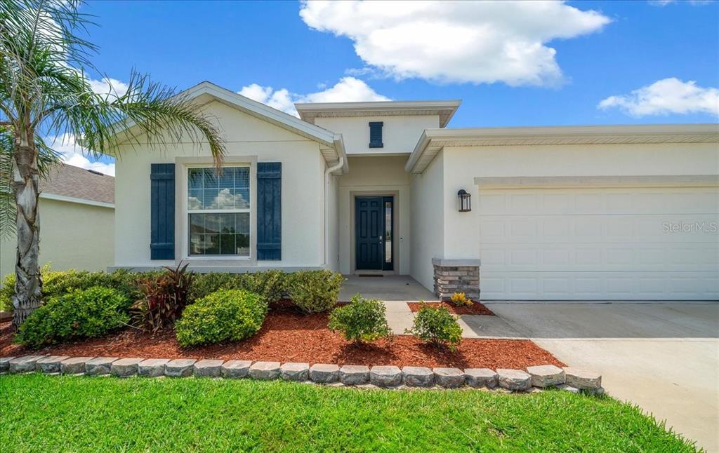 A single-story house with a white stucco exterior, blue shutters, and a two-car garage — 8068 SW 59TH TERRACE, OCALA, FL