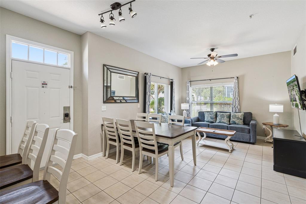 A dining area and living room with tile floors, a wooden table, and blue sofa — 2611 GALA ROAD N UNIT 108, KISSIMMEE, FL
