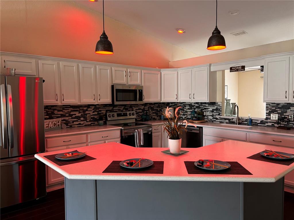 A kitchen features white cabinets, stainless steel appliances, a dark backsplash, and a peninsula island — 7855 SUGAR PINE BOULEVARD, LAKELAND, FL