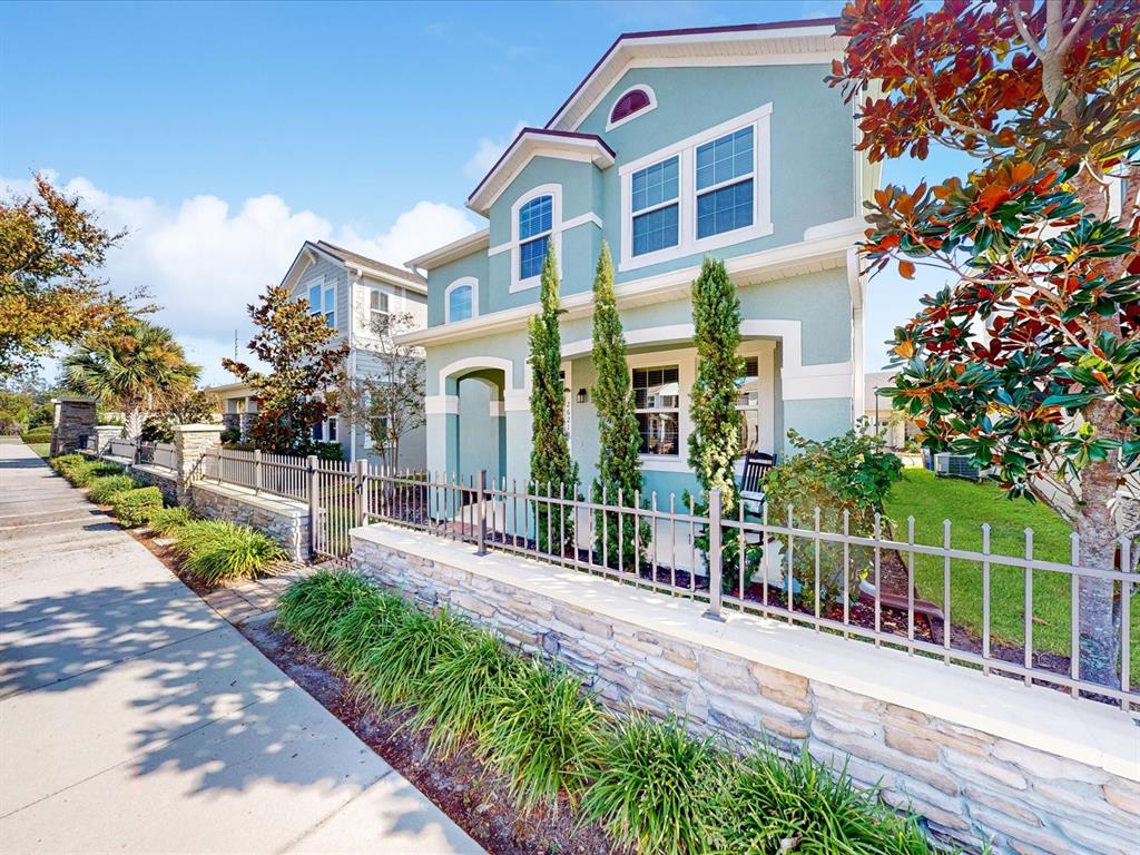 A light green two-story house features a stone-based metal fence and a sidewalk — 2621 PALISADE BOULEVARD, KISSIMMEE, FL