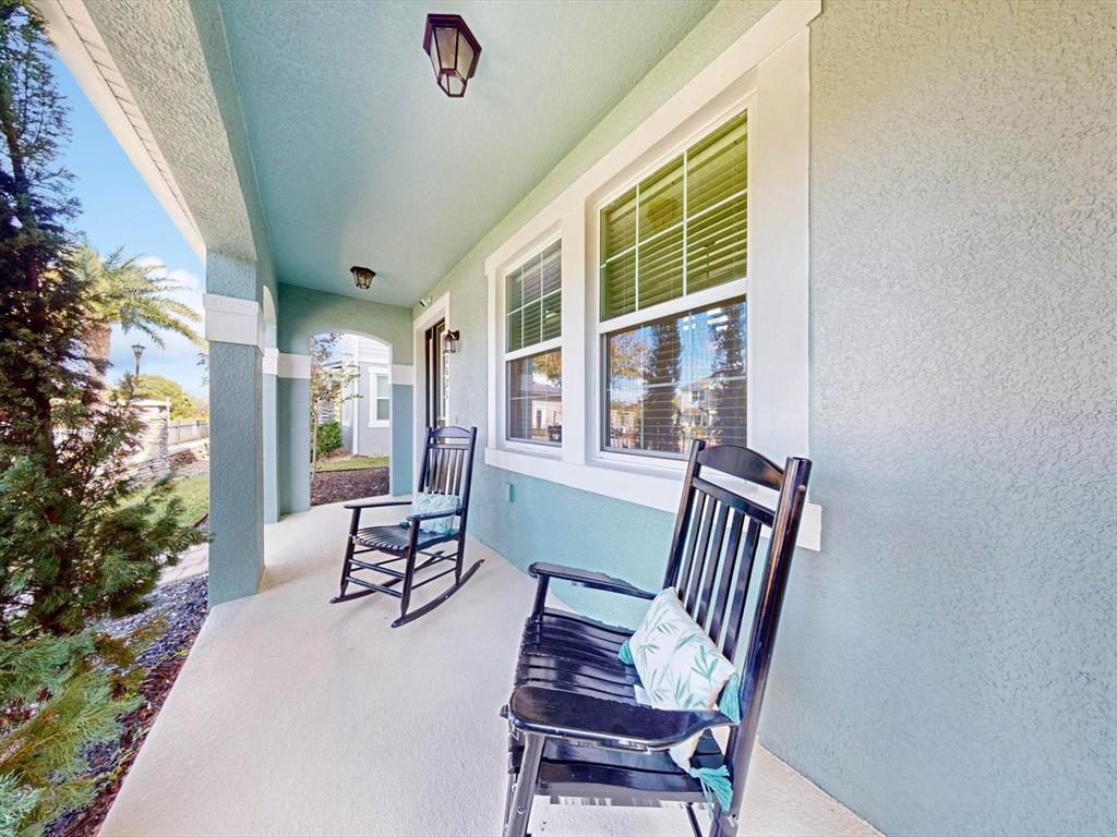 A covered porch features light blue walls, two black rocking chairs, and two ceiling lights — 2621 PALISADE BOULEVARD, KISSIMMEE, FL