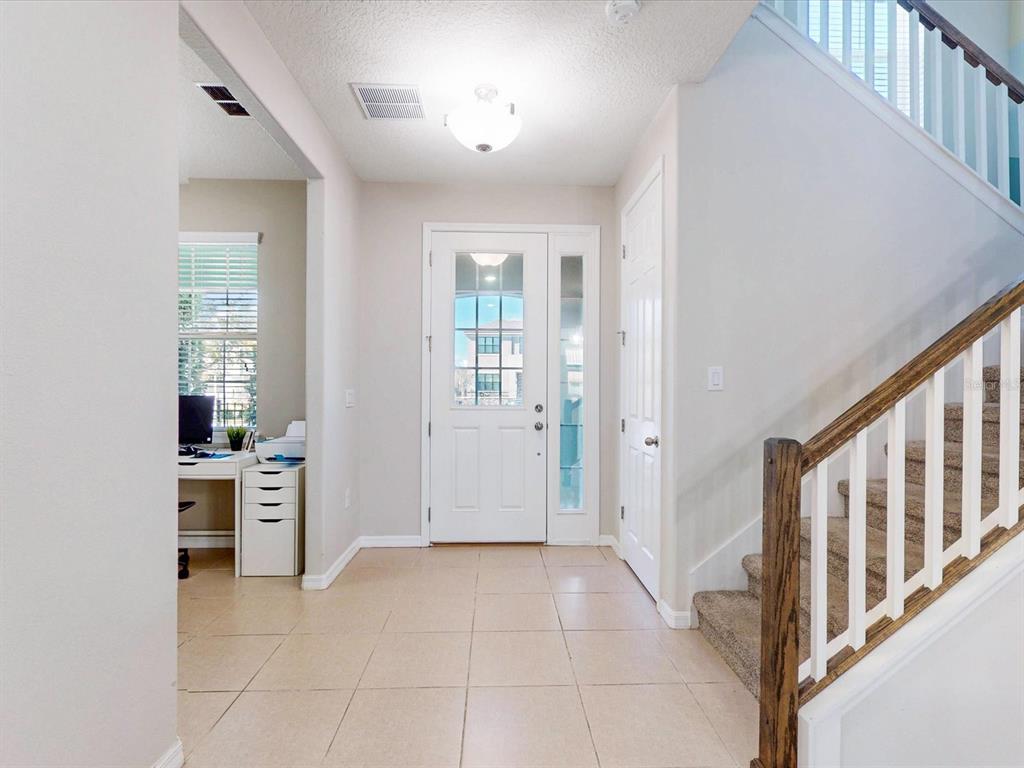 A tiled entryway features a white front door, a staircase with carpeted steps, and an office — 2621 PALISADE BOULEVARD, KISSIMMEE, FL