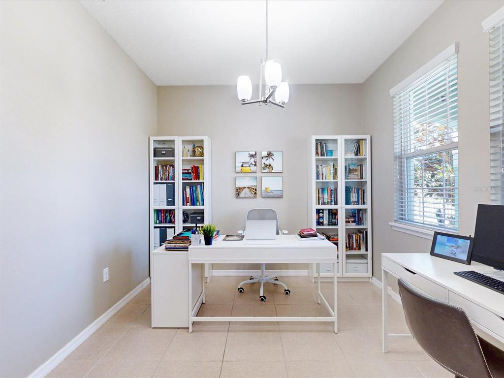 A home office features a white desk, two white bookcases, and a window with blinds — 2621 PALISADE BOULEVARD, KISSIMMEE, FL