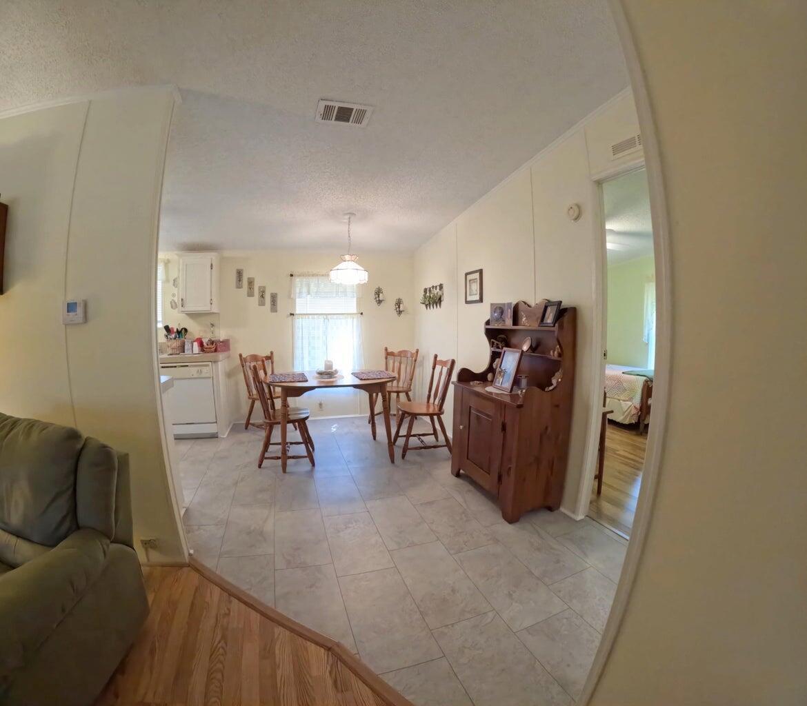 A dining area with tile flooring, a wooden table, and a hutch, adjacent to a kitchen — 6280 Cypress Lane, Lantana FL 33462, LANTANA, FL