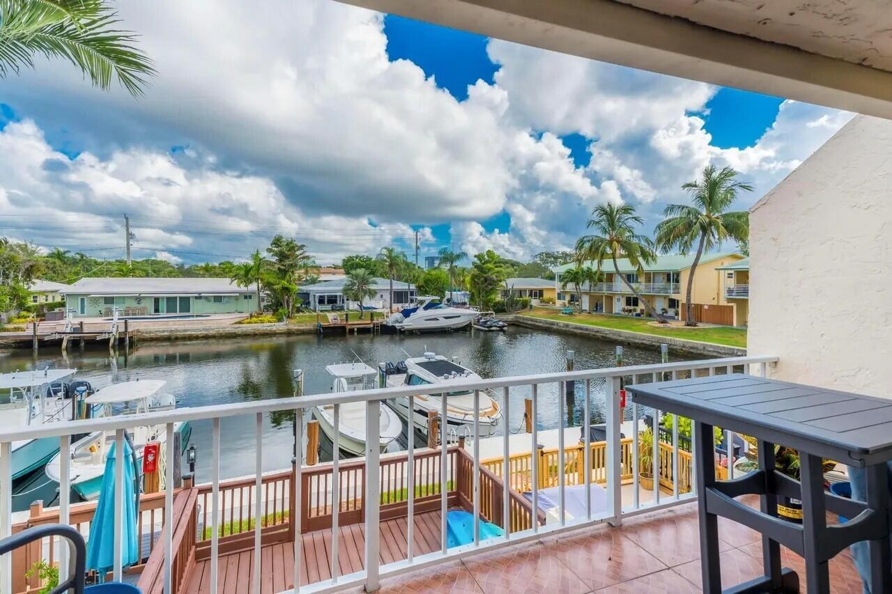 A balcony with a table overlooks a canal lined with boats and residential buildings — 1839 SE 4th Street, Pompano Beach FL 33060, POMPANO BEACH, FL
