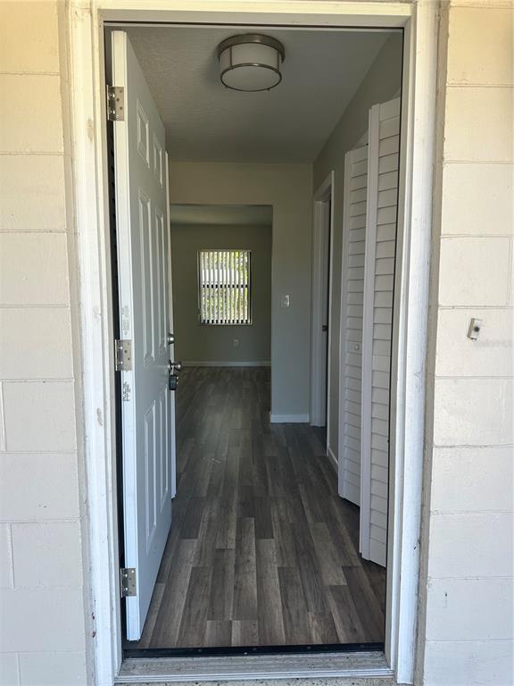 An open front door reveals a hallway with wood-look flooring leading to a living area — 1795 S LILAC CIRCLE, TITUSVILLE, FL