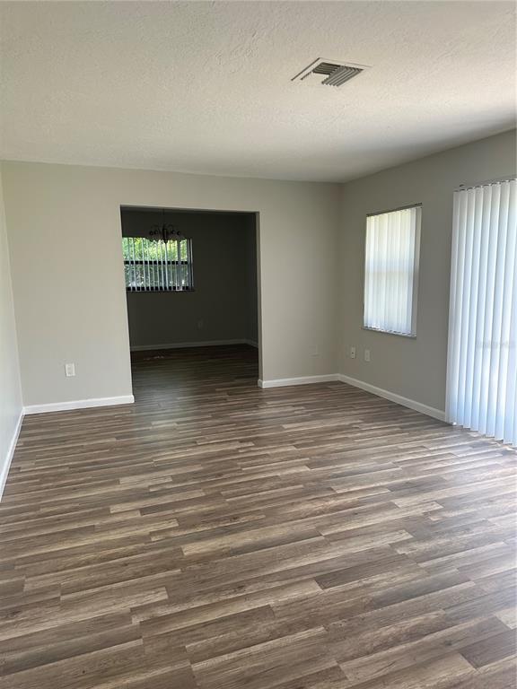 A living room with light gray walls, wood-look flooring, and vertical blinds on the windows — 1795 S LILAC CIRCLE, TITUSVILLE, FL