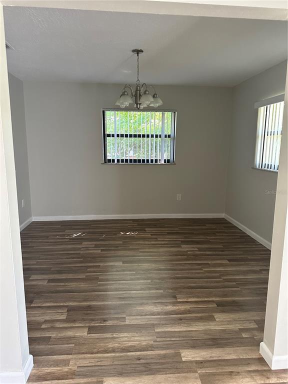 A dining room features wood-look flooring, a central chandelier, and two windows with vertical blinds — 1795 S LILAC CIRCLE, TITUSVILLE, FL