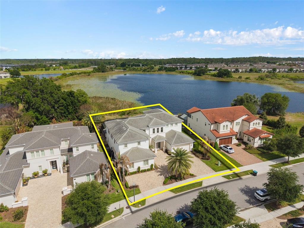 An aerial view shows a two-story house with a paved driveway beside a lake — 15522 SHOREBIRD LANE, WINTER GARDEN, FL