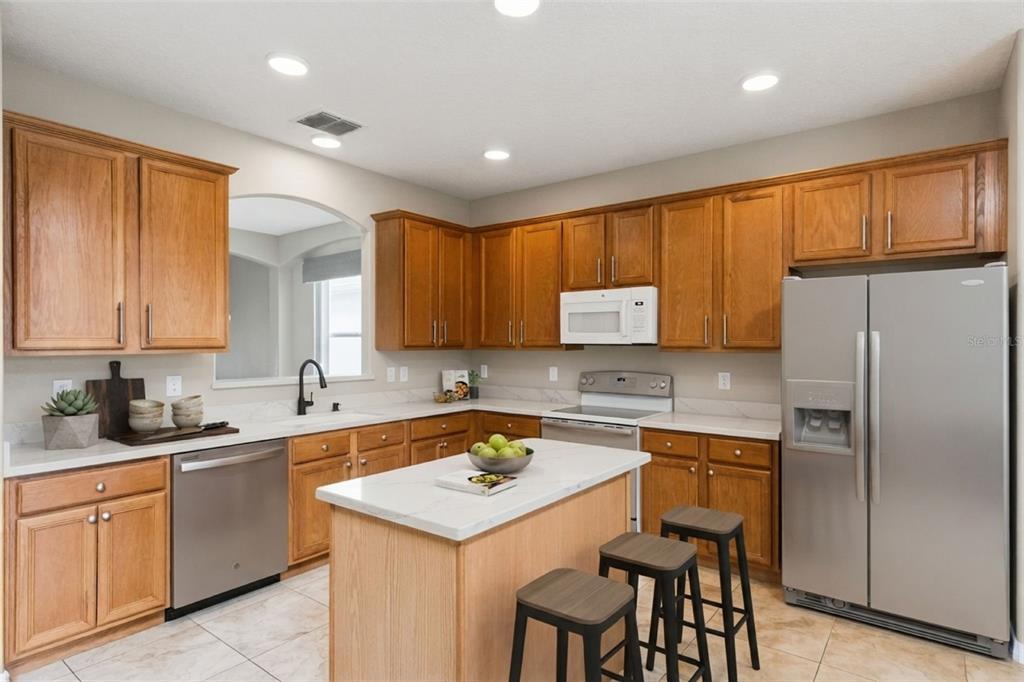 A kitchen with wood cabinets, stainless steel appliances, a center island, and white countertops — 14108 BUDWORTH CIRCLE, ORLANDO, FL