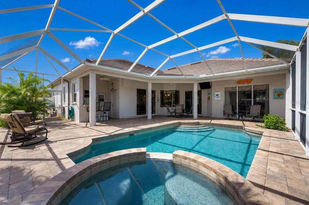 A screened-in patio features a swimming pool, a raised spa, and beige paver flooring — 7572 PALMER GLEN CIRCLE, SARASOTA, FL