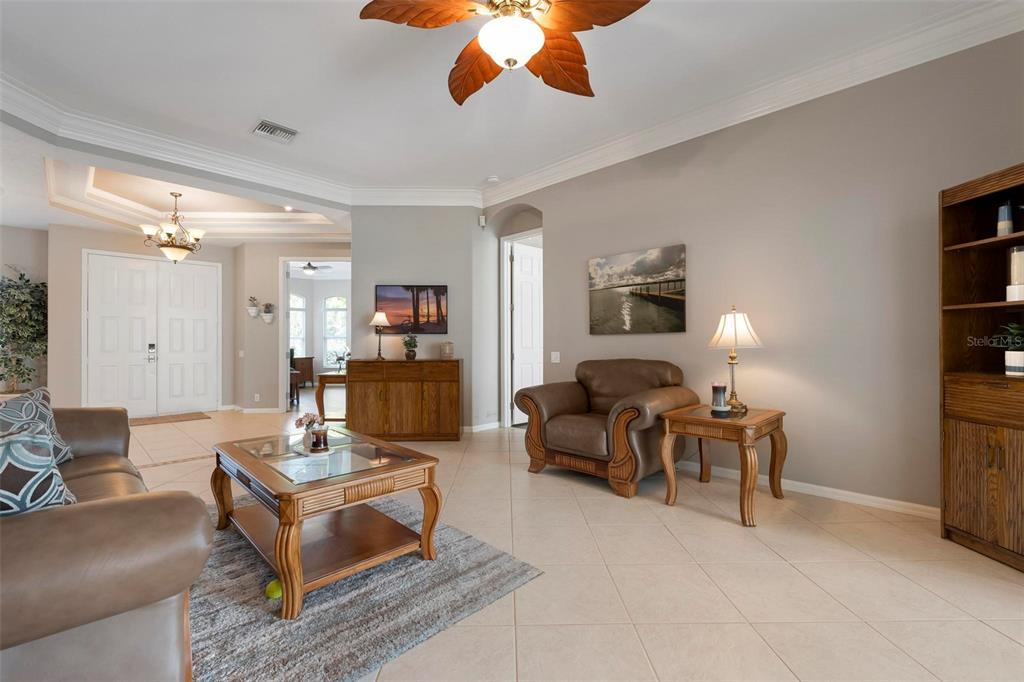 A living room with tile floors, a brown leather sofa, and a ceiling fan — 7572 PALMER GLEN CIRCLE, SARASOTA, FL