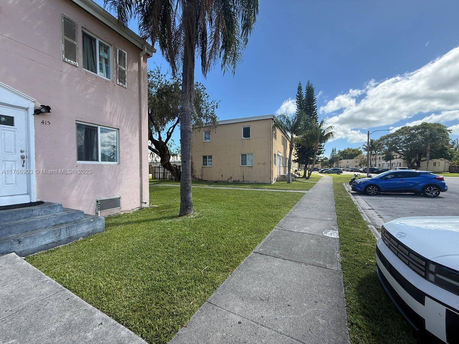 A pink apartment building stands next to a tan building with a sidewalk and parking — 417 NW 84th St # 417, Miami FL 33150, MIAMI, FL