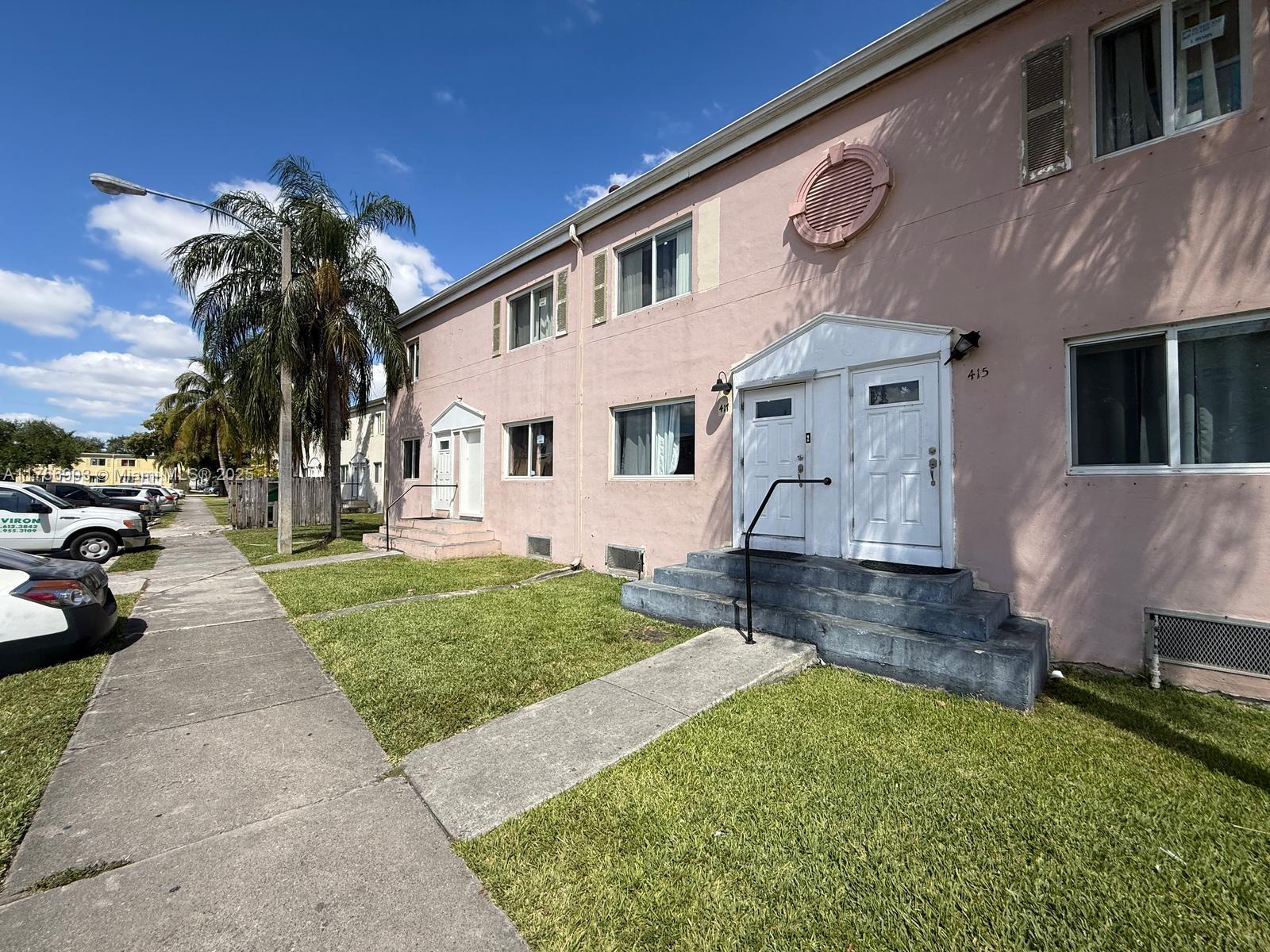 A two-story pink apartment building features white doors, concrete steps, and a grassy front yard — 417 NW 84th St # 417, Miami FL 33150, MIAMI, FL