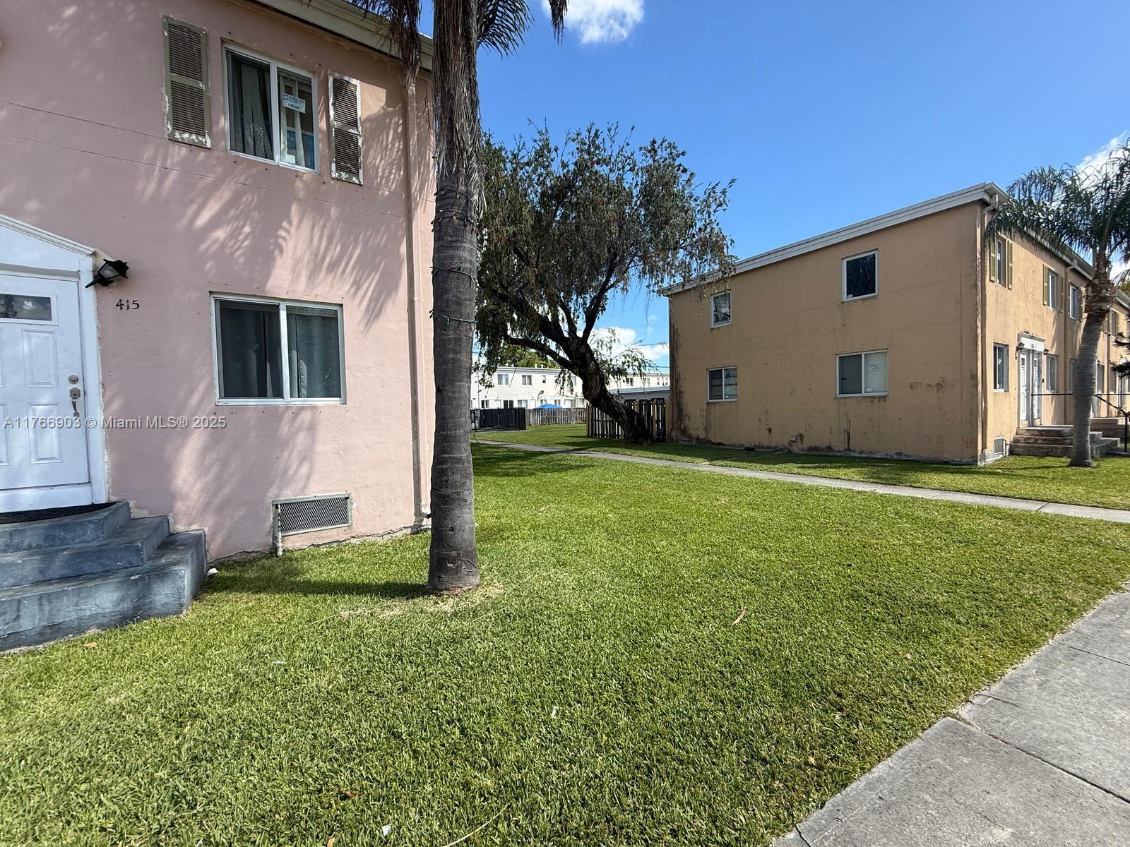 Two multi-story apartment buildings stand on a grassy lawn under a clear blue sky — 417 NW 84th St # 417, Miami FL 33150, MIAMI, FL